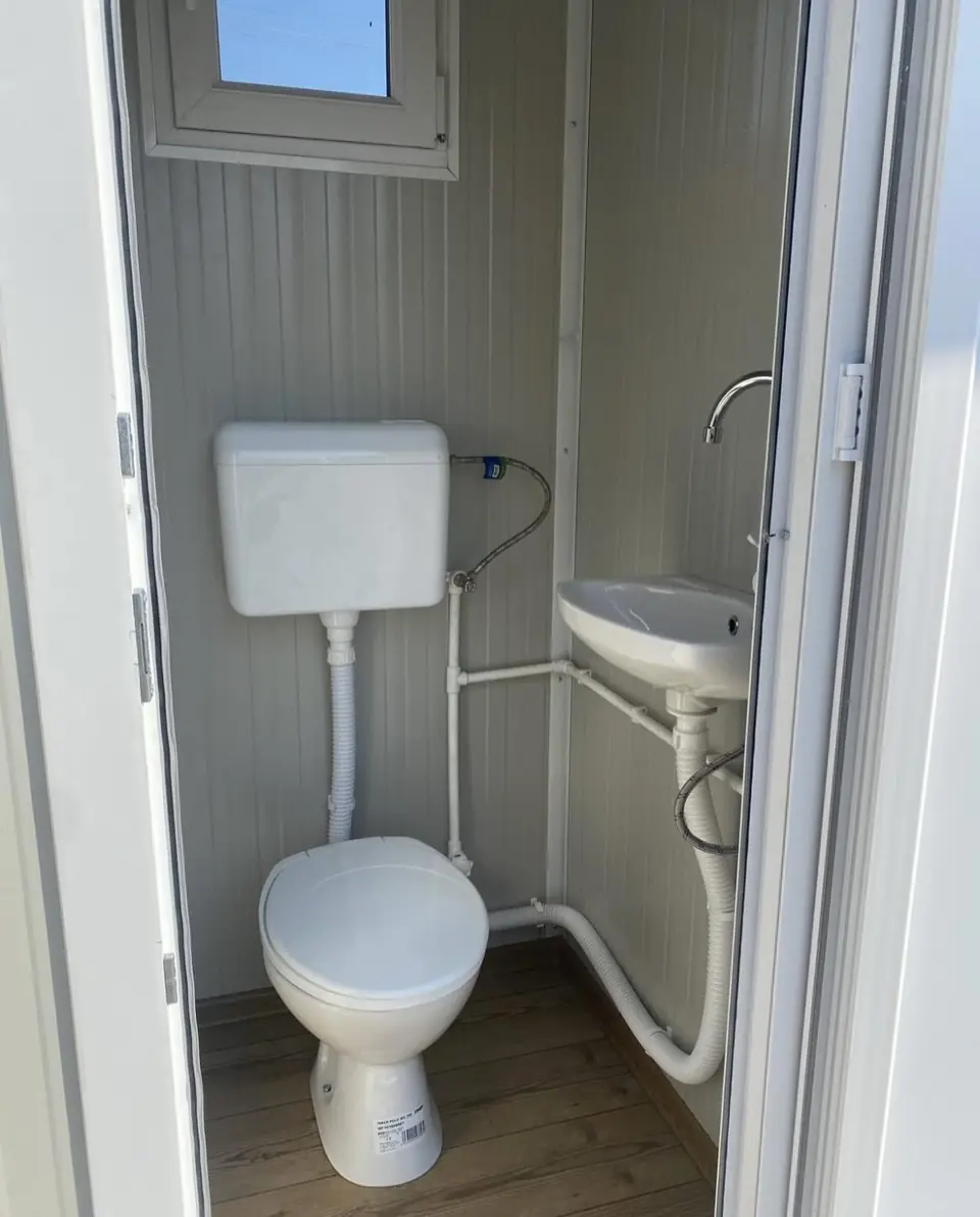 Inside a flushing restroom cabin with porcelain toilet and sink