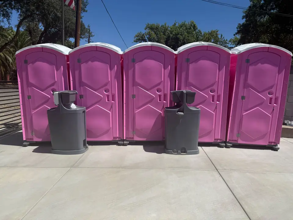 Row of pink porta potties with two hand-wash stations in front