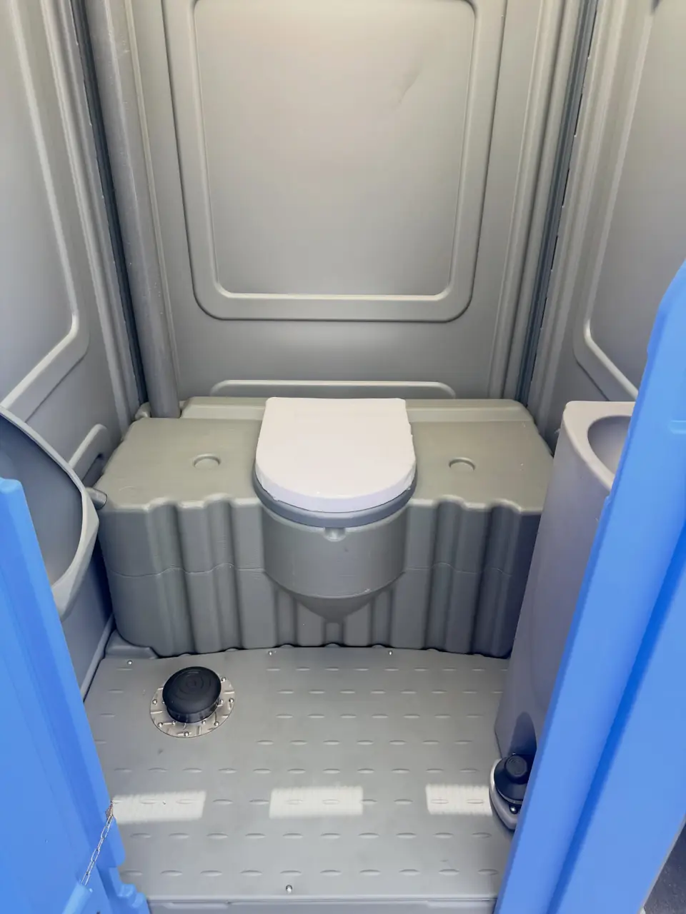 Inside a grey porta potty with a lidded seat