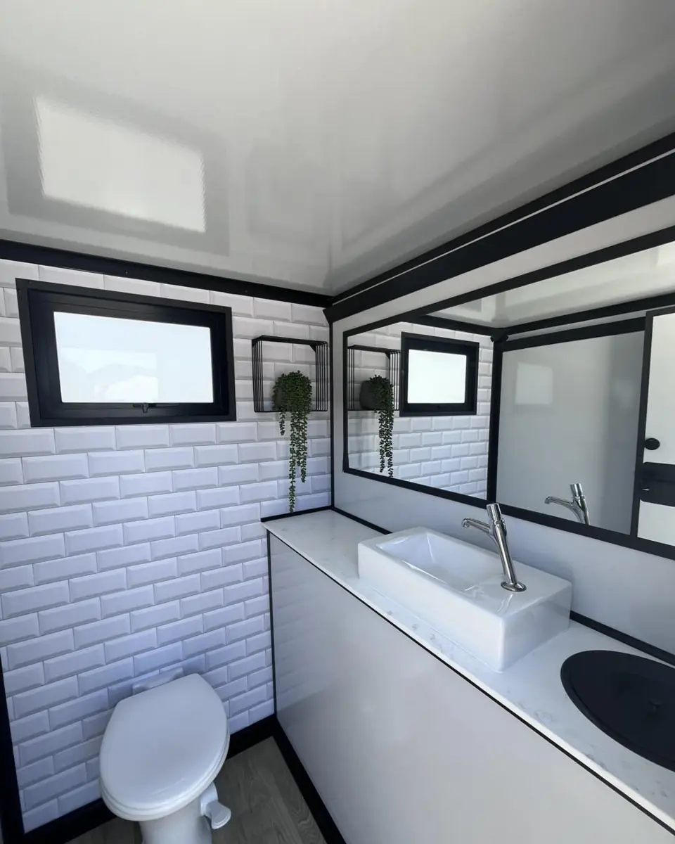 Restroom trailer interior with tile wall, vanity and toilet
