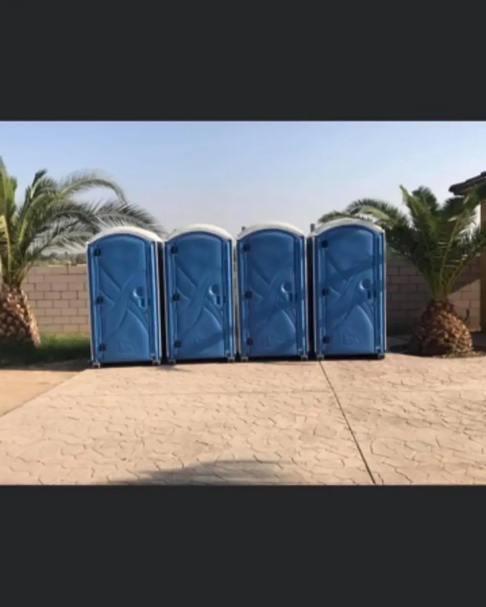 Row of four blue porta potties on concrete