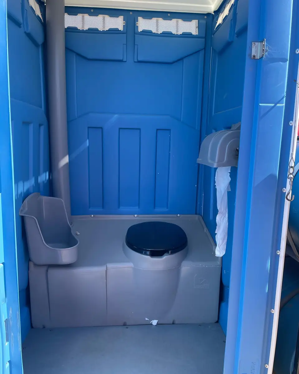 Inside a blue standard porta potty with urinal and toilet paper