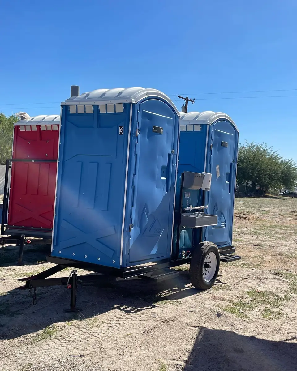 Porta potties mounted on a towable trailer at a dirt job site